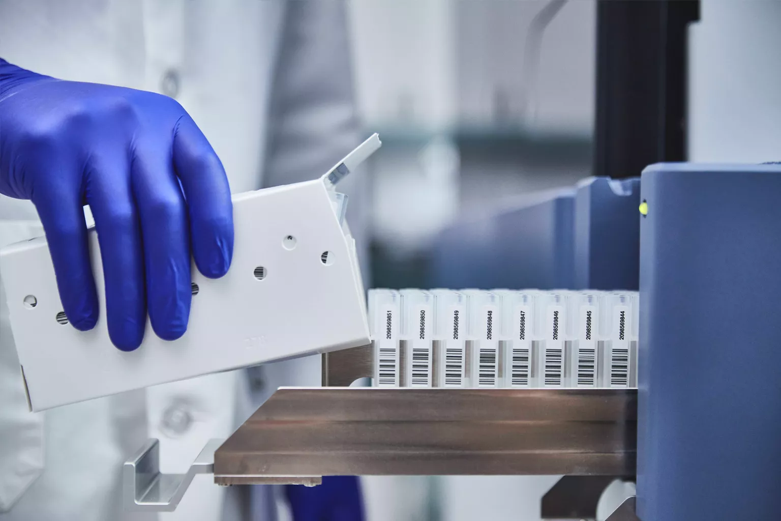 ラボの技術者がラボ内でチューブのトレイをロードしている。